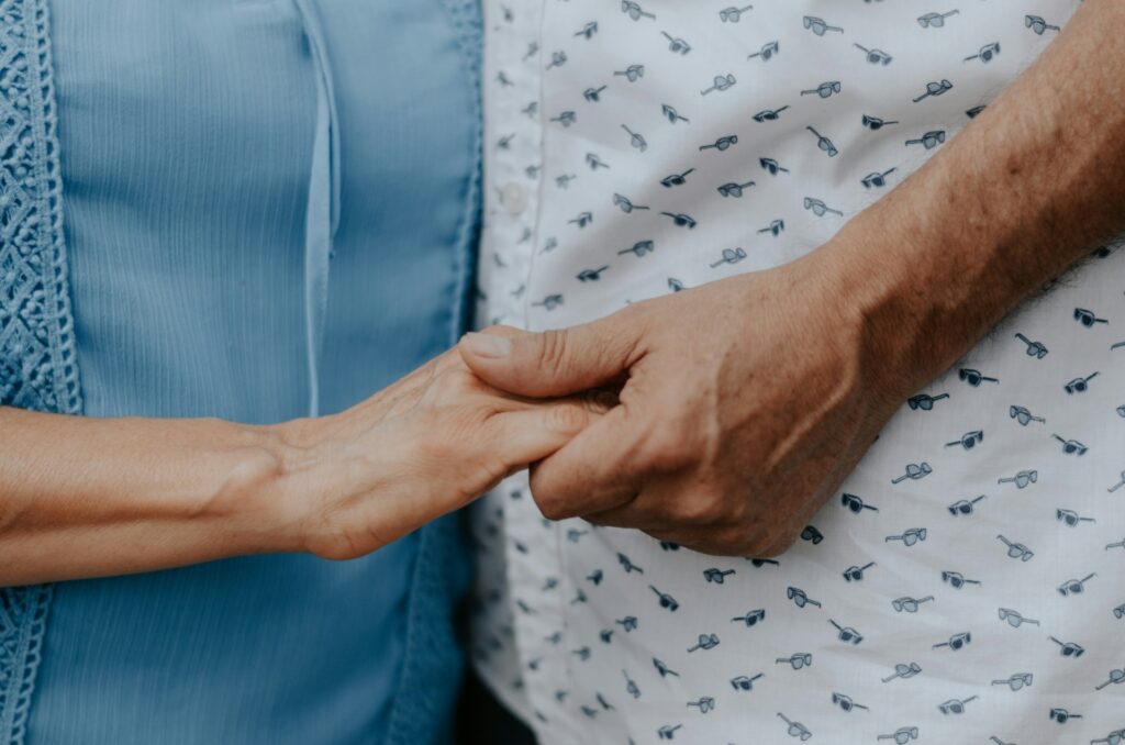 Two older people holding hands.