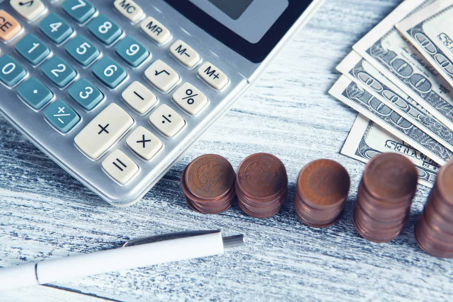 U.S. currency, a calculator and a pen on a table top.