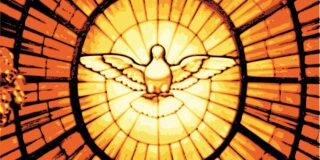 A dove is seen in a stained glass looking piece that is amber in color and representing the Holy Ghost.
