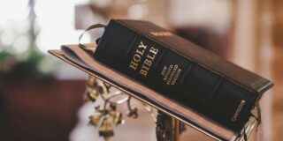 A closed black bible sits on a metal altar bookstand with the binding to the camera.