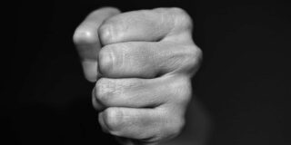 A tightly clenched fist is shown close up in the this black and white image.