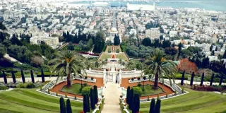Bahai Garden in Haifa, Israel is shown from above with the coast seen behind it.