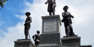 Statues of soldiers stand atop and Confederate monument.