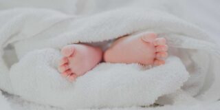 The bottoms of a baby's feet are shown wrapped in a white towel.