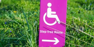 A bright pink sign shows a wheelchair graphic with the word "step free route' and an arrow.