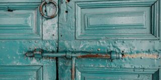 A set of old soft teal doors are shown close up with a slide lock.